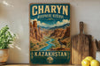 A vintage-style sign for Charyn Bioscape Reserve in Kazakhstan, featuring a mountain landscape with a river and a goat.