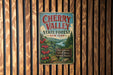 A vintage-style metal sign for Cherry Valley State Forest in New York, featuring a scenic illustration of cherry trees and a forest landscape.