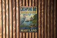A metal sign for Chesapeake Bay National Estuarine Research Reserve, featuring an illustration of a heron and a boat on the water.