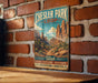 A vintage-style metal sign for Chesler Park Loop, featuring a desert landscape with mountains and trees, mounted on a brick wall.
