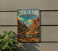 A vintage-style metal sign for Chesler Park Loop, featuring a scenic desert landscape with mountains and a trail, mounted on a wall.