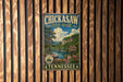 A vintage metal sign for Chickasaw State Forest in Tennessee, featuring a scenic landscape with pine trees, a lake, and mountains.