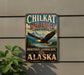 A vintage-style sign for the Chilkat Bald Eagle Preserve in Alaska, featuring an eagle in flight and a scenic landscape.