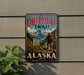 A vintage metal sign for the Chilkoot Trail in Alaska, featuring a hiker and mountainous landscape.