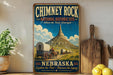 A vintage-style sign for the Chimney Rock National Historic Site in Nebraska, featuring a wagon train traveling through the landscape.