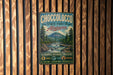 A vintage metal sign for Choccolocco State Forest in Alabama, featuring a scenic mountain landscape and text promoting outdoor activities.