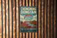 A vintage metal sign for the Hongming Don'tan Nature Reserve in China, featuring an illustration of a crane and a scenic landscape.