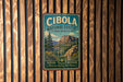 A vintage-style metal sign for the Cibola National Forest in New Mexico, featuring a scenic mountain landscape and the text "Cibola National Forest" and "New Mexico".