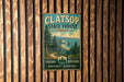 A vintage-style metal sign for Clatsop State Forest in Oregon, featuring a scenic landscape with pine trees, mountains, and a body of water.