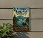 A vintage-style metal sign for Clayoquot Sound, a nature reserve in Canada, featuring an image of a whale and a forest landscape.
