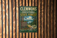 A vintage-style metal sign for Clemmons Educational State Forest, featuring a scenic landscape with pine trees and a lake.