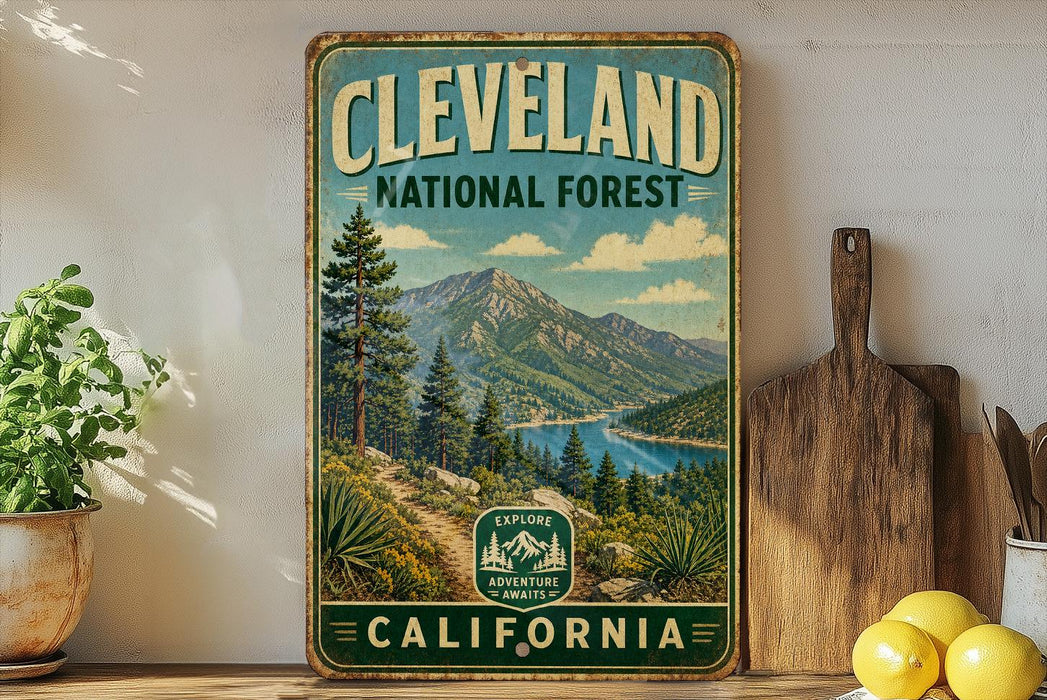 A vintage-style metal sign for Cleveland National Forest, featuring a scenic mountain landscape with a lake and pine trees.