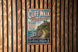 A vintage-style metal sign for Cliff Walk, Rhode Island, featuring a scenic coastal view and a path leading to a house on the cliff.