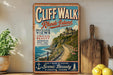 a vintage-style sign for Cliff Walk, Rhode Island, with a scenic coastal view and a wooden paddleboard.