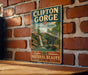 A vintage-style metal sign for Clifton Gorge State Nature Preserve, featuring a scenic image of a waterfall and lush greenery.