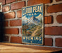 A vintage-style metal sign for the Cloud Peak Trail in Wyoming, featuring a mountain landscape and trail sign.