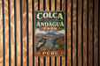 A vintage metal sign with the text "COLCA Y VOLCANES DE ANDAGUA PARK PERU" is displayed on a wooden wall.