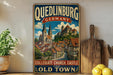 A vintage-style metal sign advertising Quedlinburg, Germany, featuring a castle and a town scene.