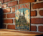A vintage metal sign displaying the image of the Cologne Cathedral in Germany, with the text "Cologne Germany" and "The Cathedral City - Culture - History - Tradition".