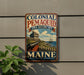 A vintage-style metal sign for Colonial Pemaid, a state historic site in Maine, featuring a cannon and a ship on a coastal landscape.
