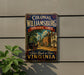 A vintage-style metal sign for the Colonial Williamsburg Historic Area in Virginia, featuring an illustration of a horse-drawn carriage and a town scene.