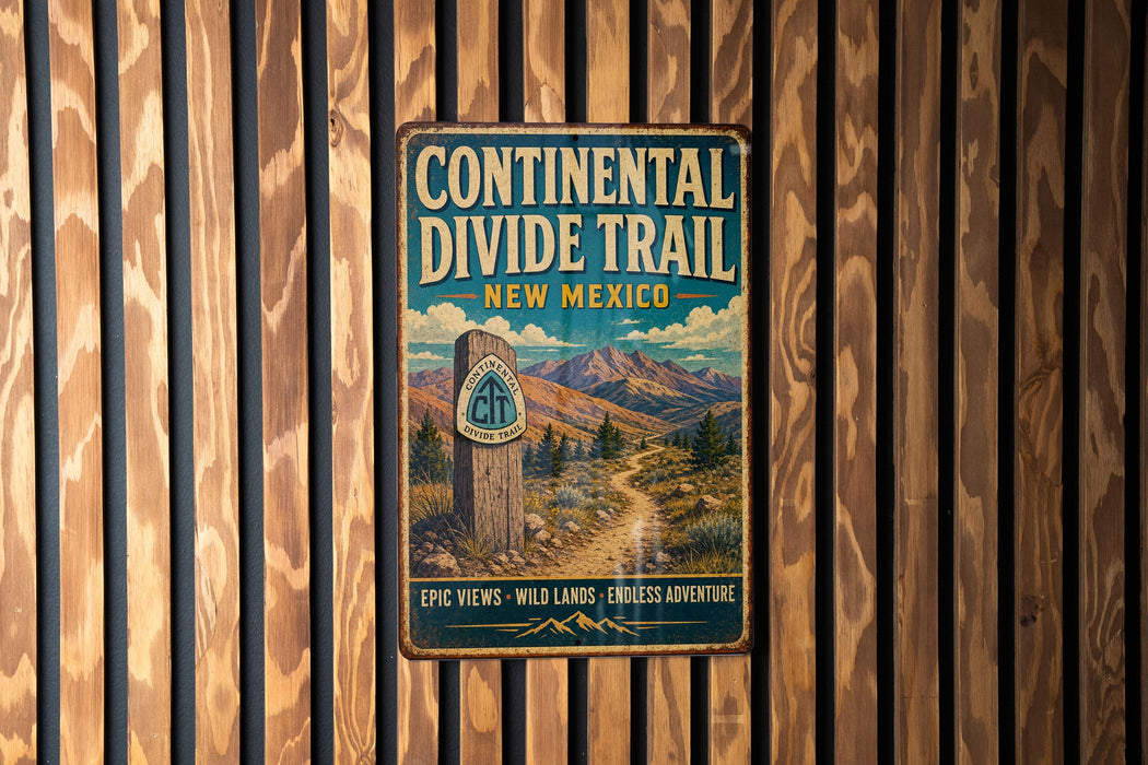 A vintage metal sign for the Continental Divide Trail in New Mexico, featuring a scenic mountain landscape and the trail's name.