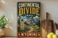 A vintage-style metal sign for the Continental Divide Trail in Wyoming, featuring a mountain landscape and trail marker.