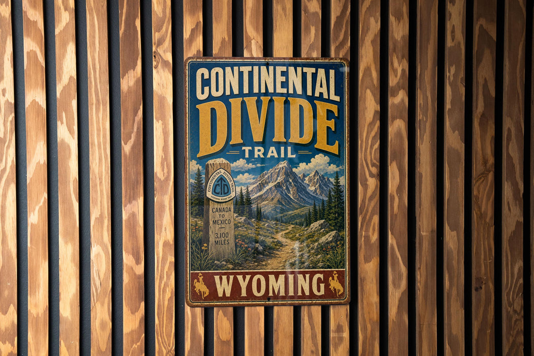 A metal sign with the text "CONTINENTAL DIVIDE TRAIL" and "WYOMING" is displayed on a wooden wall.
