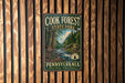 A vintage metal sign for Cook Forest State Park in Pennsylvania, featuring a scenic image of a forest and a river.