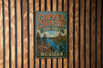 A vintage metal sign for Copper Country State Forest in Michigan, featuring a scenic illustration of a river, mountains, and forests.