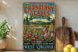A vintage-style sign advertising cranberry glades, a botanical area in West Virginia, with a scenic landscape featuring a river and pine trees.