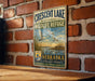 A vintage metal sign for the Crescent Lake National Wildlife Refuge in Nebraska, featuring a serene image of ducks swimming in a lake.