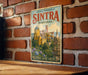 A vintage-style metal sign with the text "CULTURAL LANDSCAPE OF SINTRA PORTUGAL" and an illustration of a castle surrounded by trees and flowers.