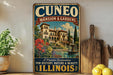 a vintage-style sign for Cuneo Mansion & Gardens, which is described as a "Premier Destination for History, Nature & Beauty Illinois". The sign is displayed on a wooden shelf, with a potted plant and a cutting board nearby.