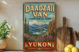 a vintage-style sign for Dáadzálí Ván, a famous park in Yukon, Canada. The sign is displayed on a wooden shelf, surrounded by various kitchen utensils and a potted plant.