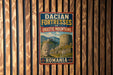 A vintage metal sign with the text "DACIAN FORTESSES OF ORASTIE MOUNTAINS ROMANIA" is displayed on a wooden wall.