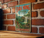A vintage-style sign for Dak Nong Park, featuring a waterfall and lush greenery, is displayed on a brick wall.