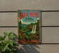 A vintage metal sign for Dak Nong Park in Vietnam, featuring a scenic landscape with a waterfall and lush greenery.