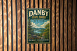 A vintage-style metal sign for Danby State Forest in New York, featuring a scenic landscape with pine trees, a lake, and mountains.