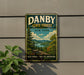 A vintage-style metal sign for Danby State Forest in New York, featuring a scenic landscape with pine trees, mountains, and a river.