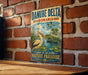 A vintage metal sign with the text "DANUBE DELTA ROMANIA" and an illustration of a pelican in a pond, surrounded by lush greenery, is displayed on a brick wall.