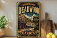 a vintage-style metal sign for the historic district of Deadwood, South Dakota, with a picture of a saloon and a horse-drawn carriage.