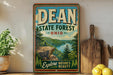 A vintage-style sign for the DEAN State Forest in Ohio, featuring a scenic landscape with a river and mountains.