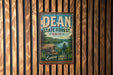 A vintage-style metal sign for the Dean State Forest in Ohio, featuring a scenic landscape with a lake and mountains.