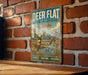 A vintage-style metal sign with a deer and ducks in a natural setting, mounted on a brick wall.