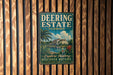 A vintage-style metal sign for "Deering Estate" in Florida, featuring a tropical landscape with palm trees and a building, is displayed on a wooden wall.