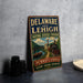 A vintage-style metal sign for the National Heritage Corridor in Delaware and Lehigh, Pennsylvania, featuring an illustration of a train and a scenic landscape.