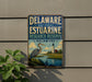 A metal sign for the Delaware National Estuarine Research Reserve, featuring a blue heron and a lighthouse in the background.