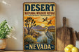 A vintage-style sign for the Desert National Wildlife Refuge in Nevada, featuring a desert landscape with a bird and a sunset.