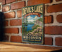 A vintage-style metal sign for Devil's Lake State Park in Wisconsin, featuring a scenic landscape with a lake, mountains, and trees.